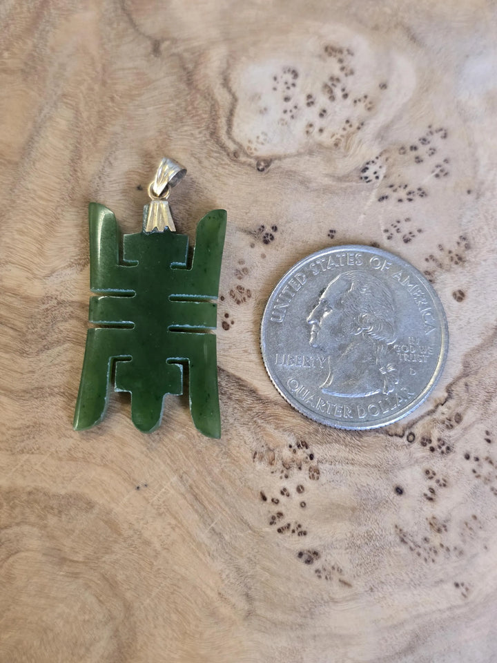 Vintage Chinese longevity pendant carved from green nephrite jade with a 14k plated bail shown beside a dime for scale