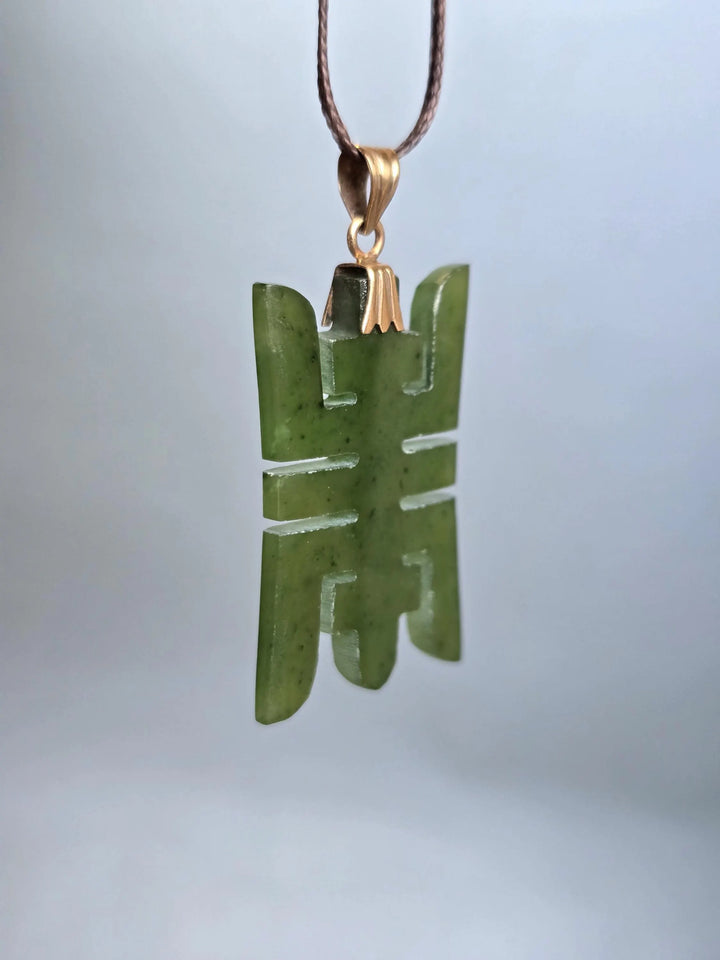 Green Canadian nephrite jade longevity pendant with a 14k plated bail on a brown cord