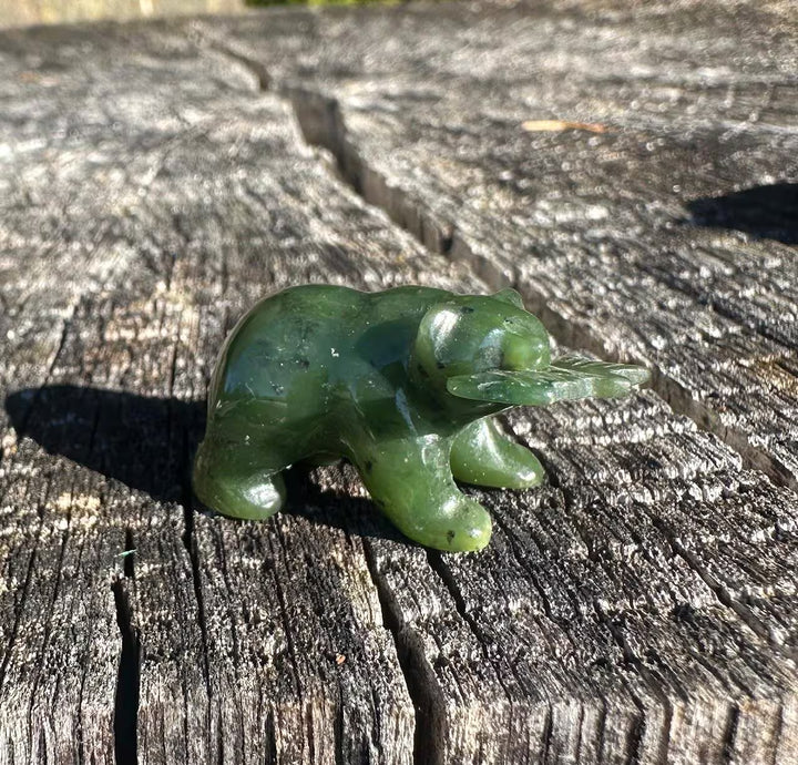 Green jade bear with leaf base outdoors on a weathered wooden surface