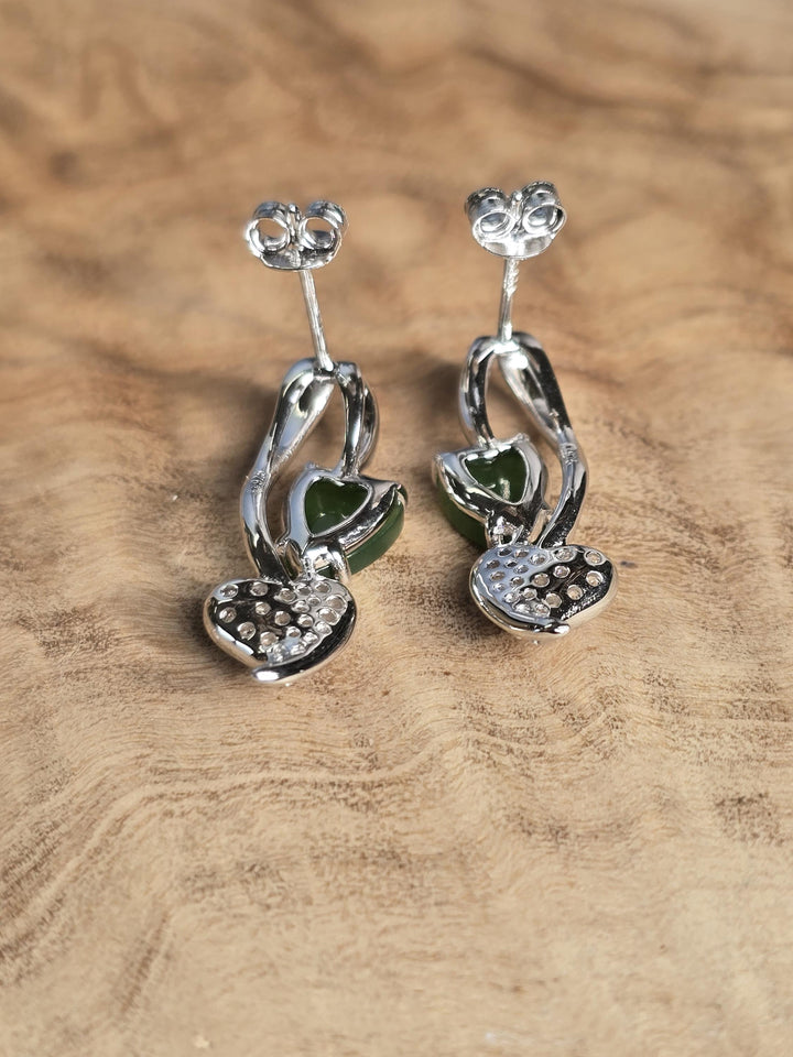 Silver earrings with green gemstones on a wooden surface