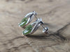 Silver earrings with green leaves on a wooden surface
