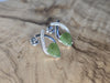 Silver earrings with green leaf designs on a wooden surface