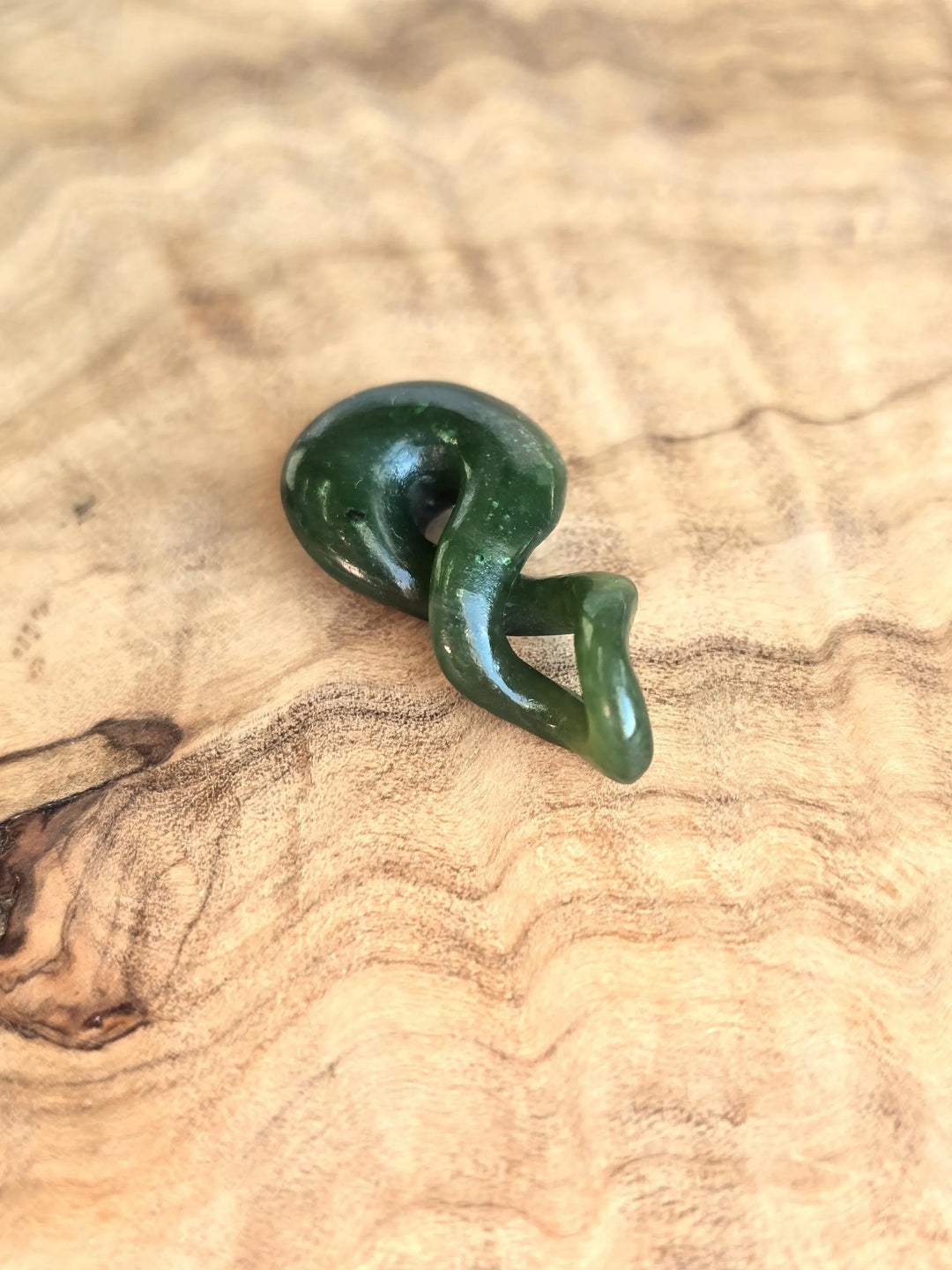 Green jade twist pendant on wooden base