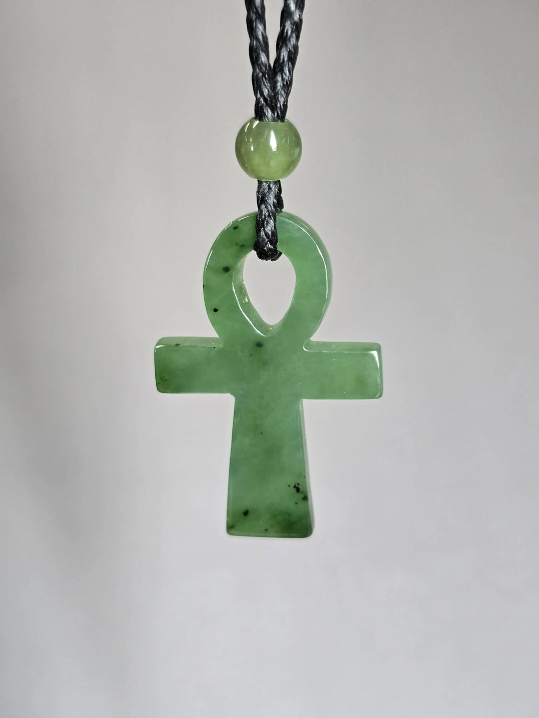 Green nephrite jade ankh pendant on a black braided cord with a round bead above the loop