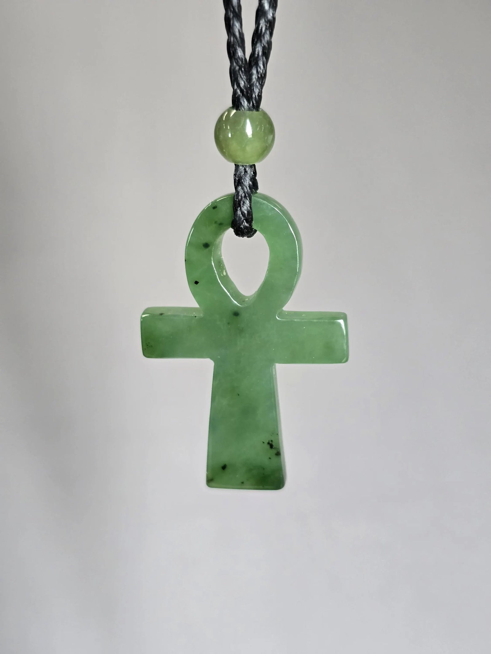 Green nephrite jade ankh pendant on a black braided cord with a round bead above the loop