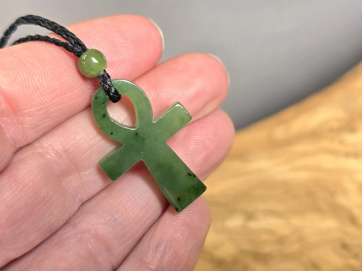 Canadian nephrite jade Ankh pendant 22x34mm held on black cord near fingers