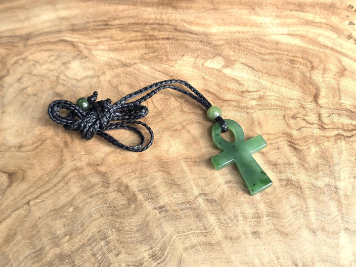 Canadian nephrite jade Ankh pendant 22x34mm on black braided cord with a green bead on a wood surface