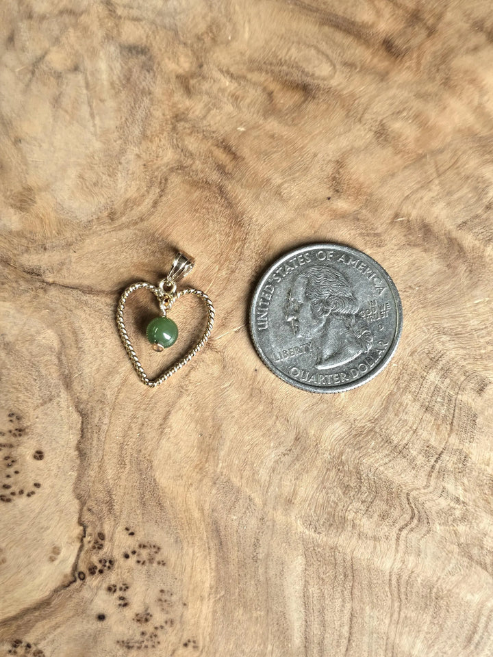 Vintage gold rope heart pendant with green nephrite jade bead beside a quarter for scale on a wood surface
