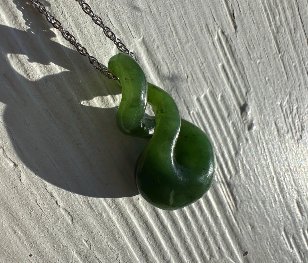 Green jade necklace with a unique design on a light gray surface