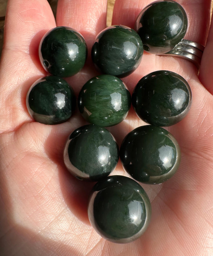 Group of polished dark green nephrite jade beads held in the hand