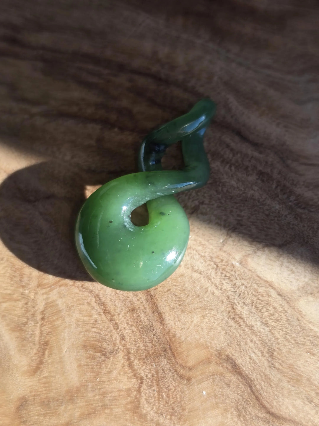 Green jade pendant on a wooden surface