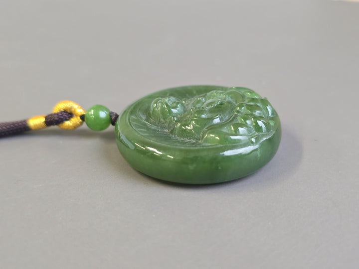 Green nephrite jade Buddha lotus pendant on a dark braided cord with a green bead