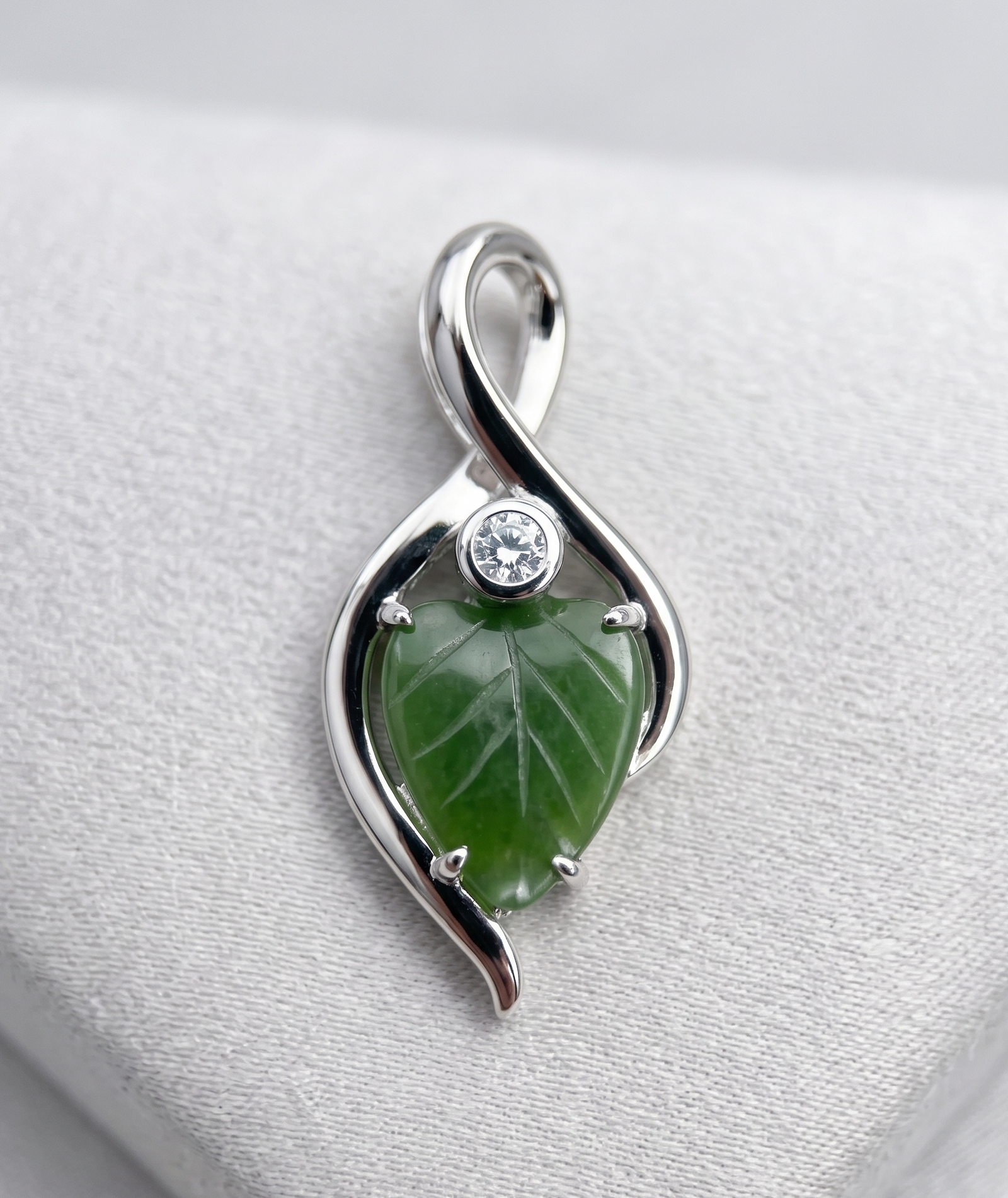 Canadian Jade Leaf and Silver Infinity Pendant featuring a green jade leaf set inside a looping silver infinity frame with a small crystal accent