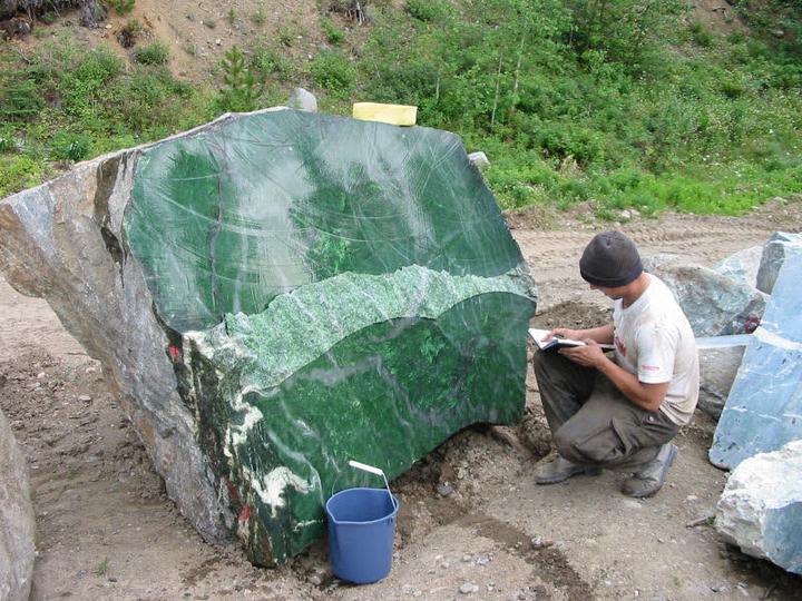 Image of Polar Pride Jade Boulder,with Andrew knealing down beside it taking notes, also blue bucket infront