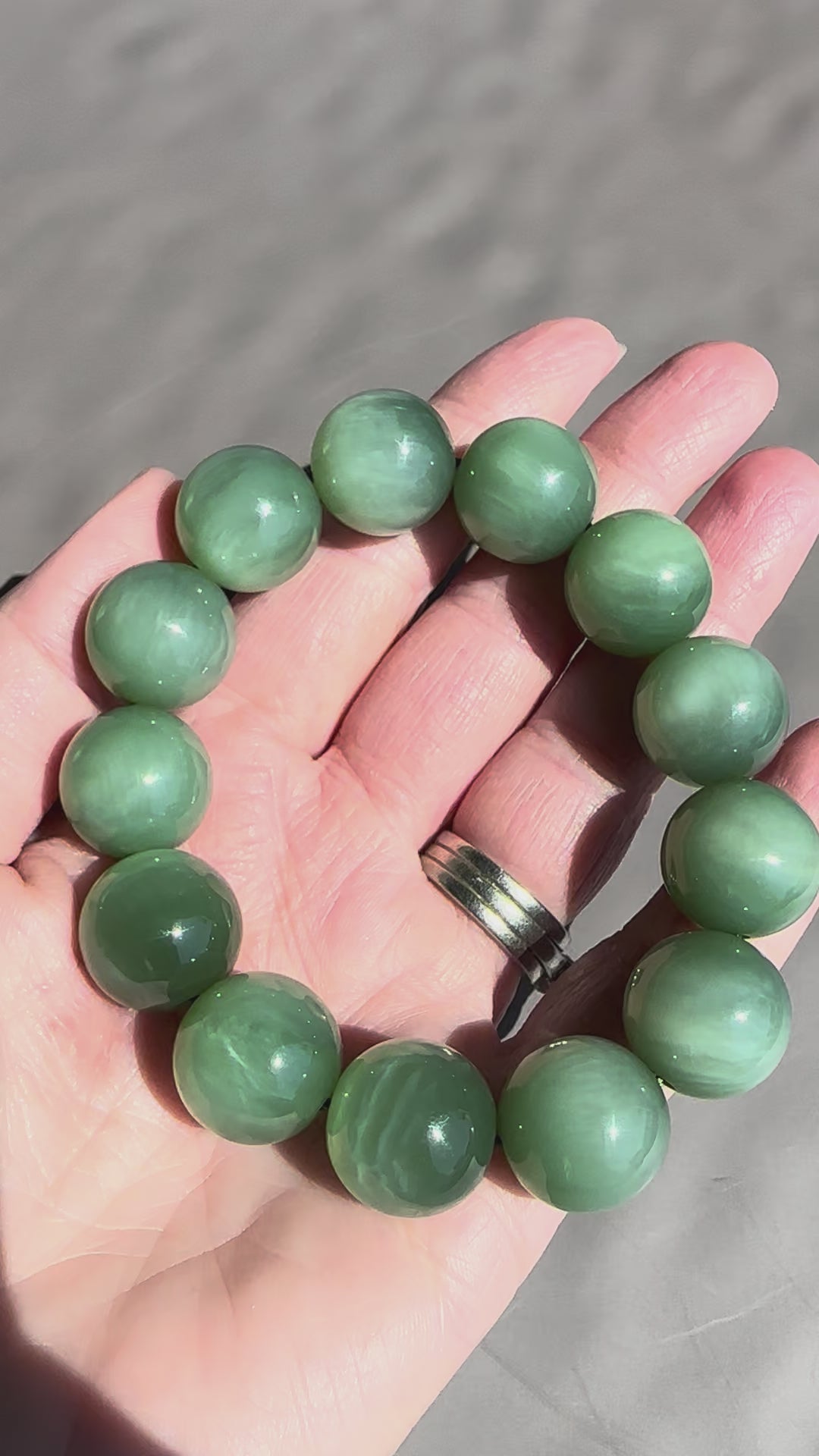 Jade being moved to see chatoyant effect grey background in hand