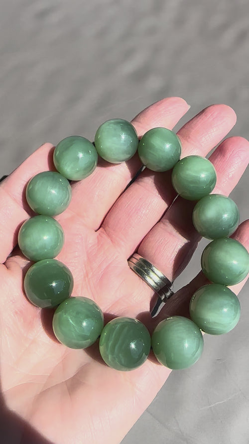 Jade being moved to see chatoyant effect grey background in hand
