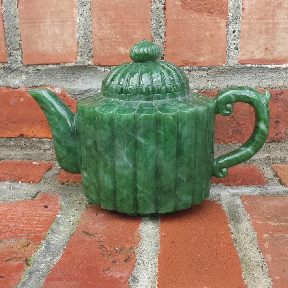 Jade teapot with lid on, features a ribbed green body, spout to the left and curved handle to the right.