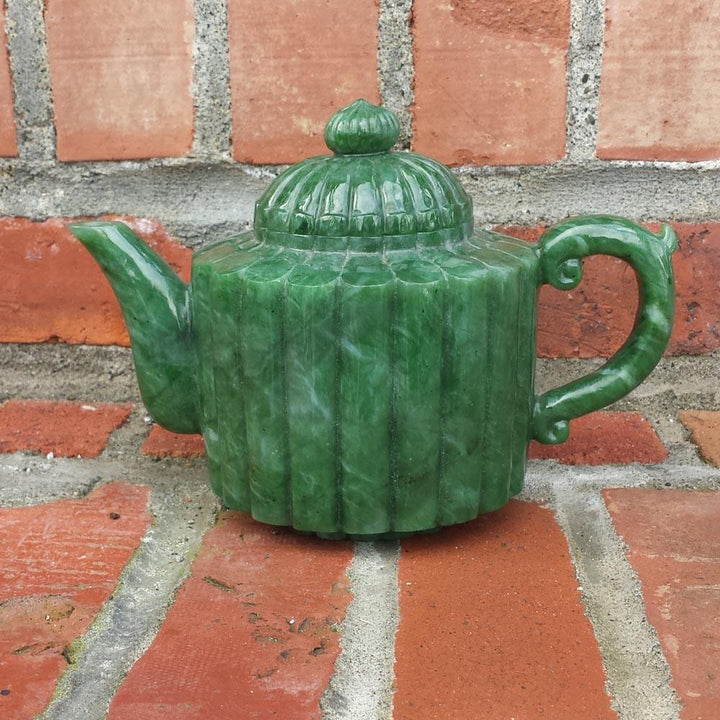 Jade teapot with lid on, features a ribbed green body, spout to the left and curved handle to the right.