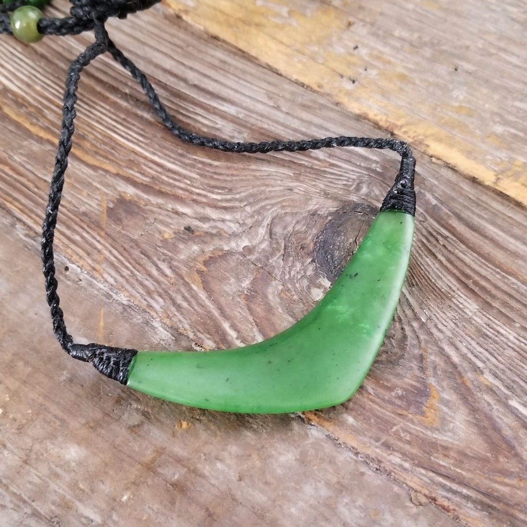 Close up of the green jade pendant on a black braided cord with tightened ends