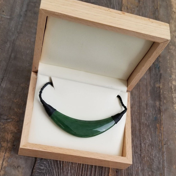 Green jade pendant in an open wooden jewelry box