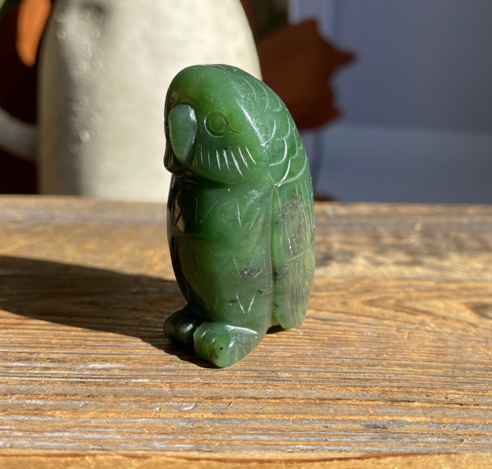 Front view of green jade owl figurine showing beak and carved feather details.