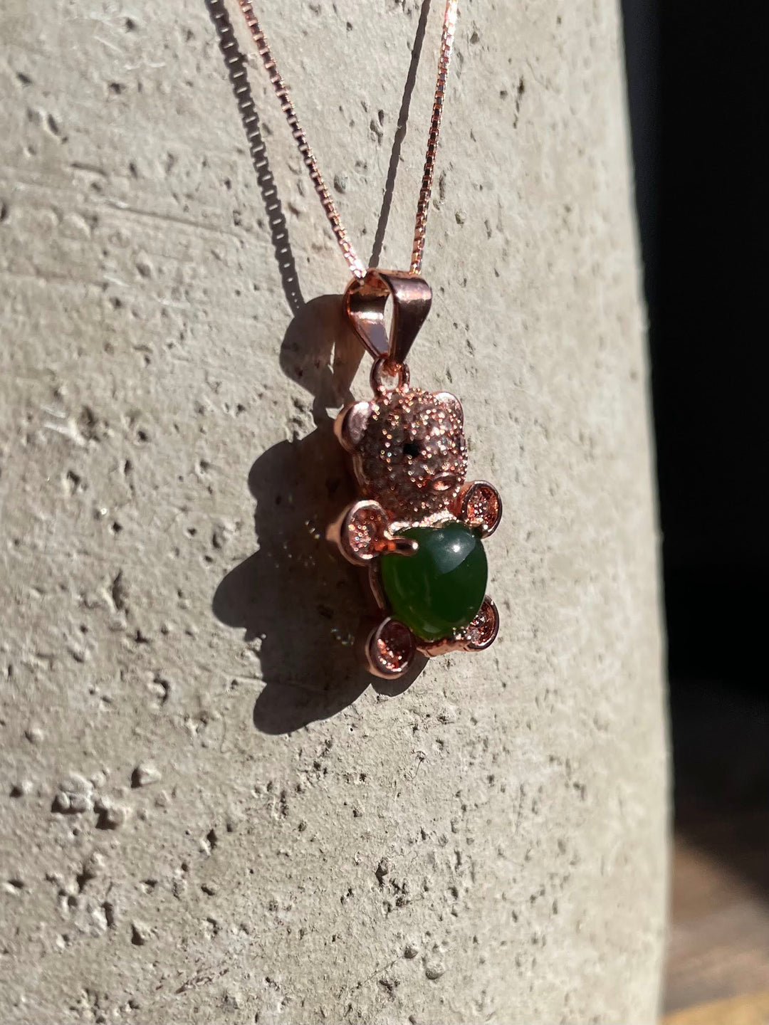 Copper rose gold bear pendant encrusted with crystals holding a green jade cabochon