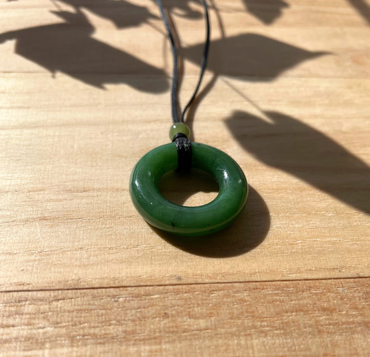 Green nephrite jade donut pendant on a black cord