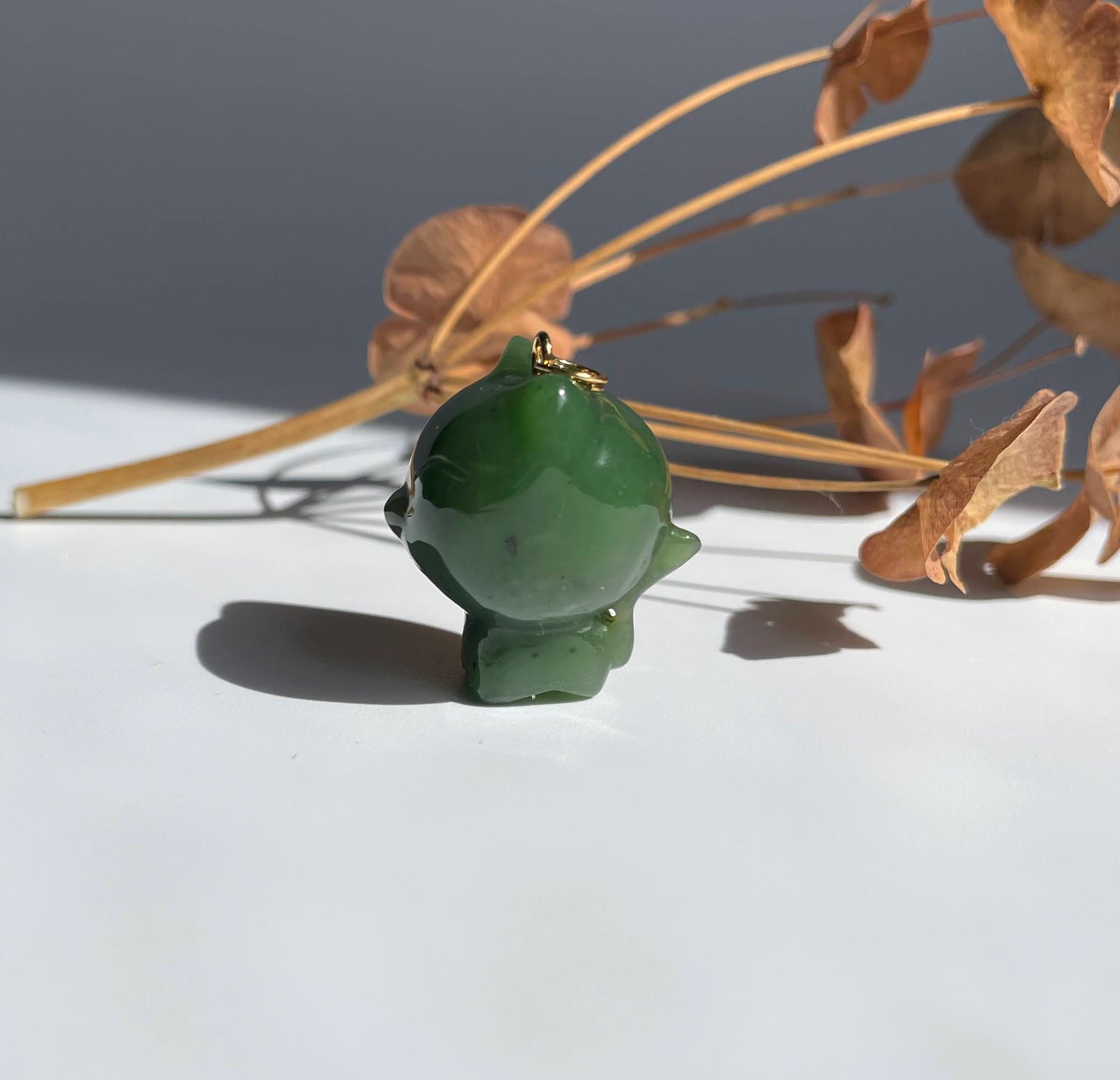 Back view of green jade cartoon cat charm with a gold loop