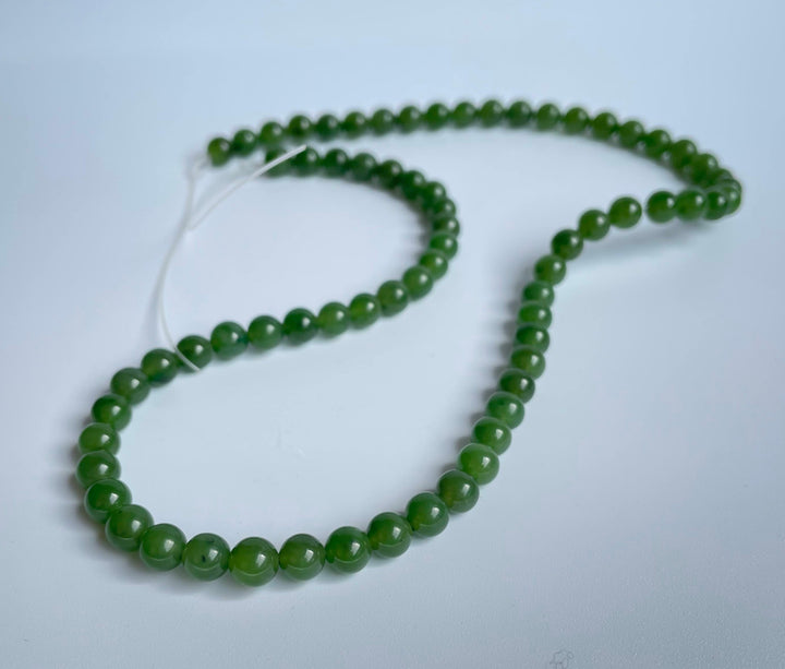 Green 6mm beads arranged in a loose strand on a white background