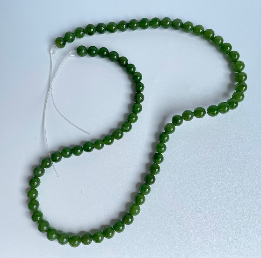 Green 6mm round beads on white thread forming an unstrung 16 inch strand