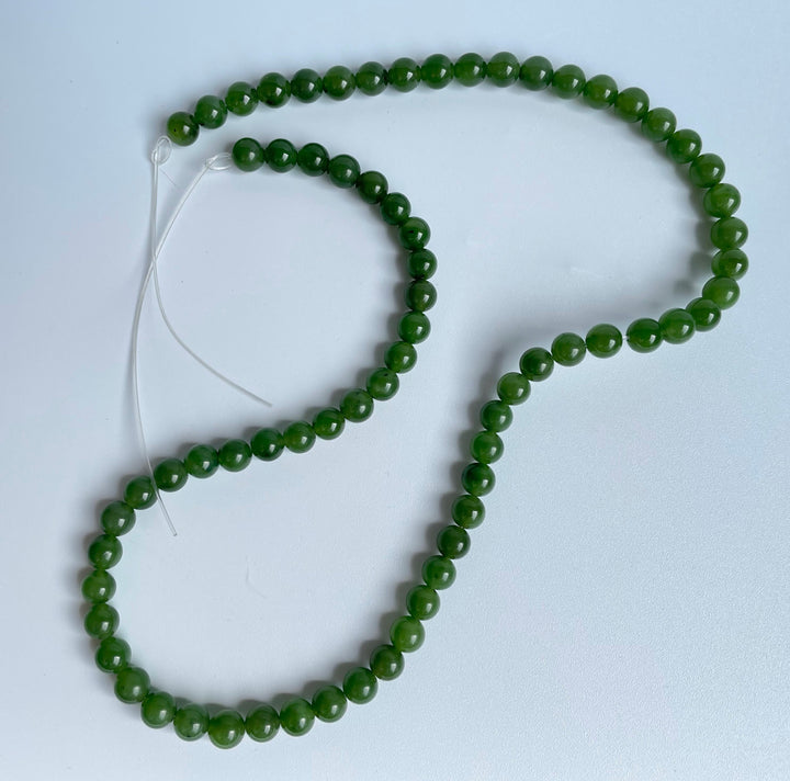 Green 6mm round beads on white thread forming an unstrung 16 inch strand
