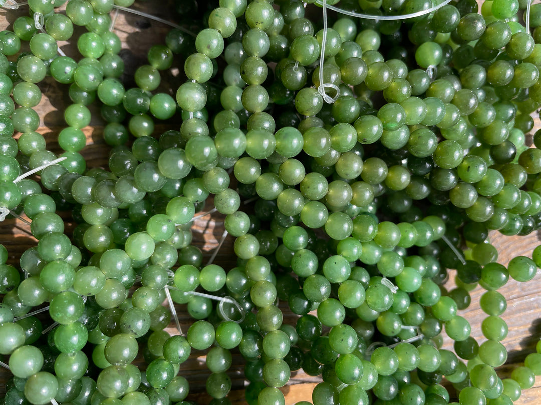 Close up of glossy green 6mm beads with white thread ends