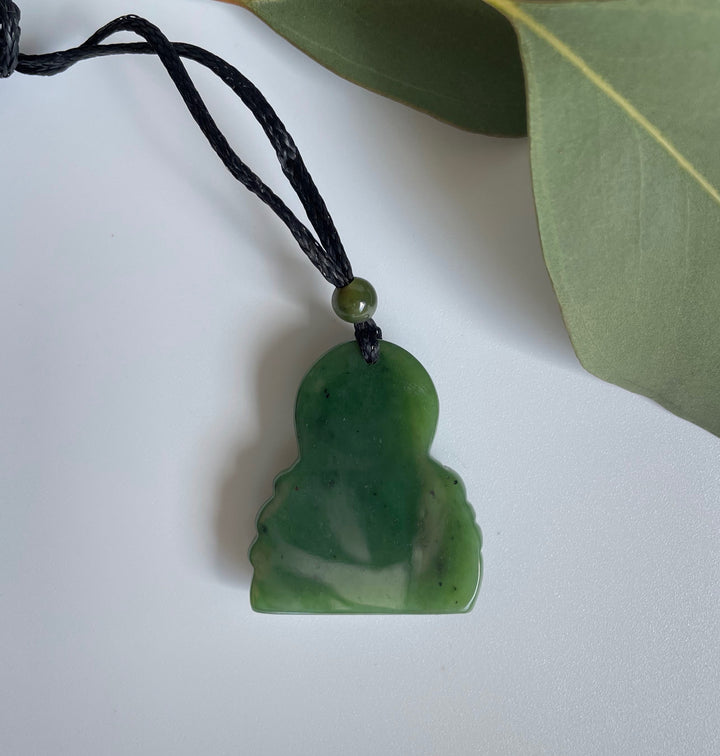 Smiling green jade Buddha pendant on a black braided cord with a small green bead near the top.