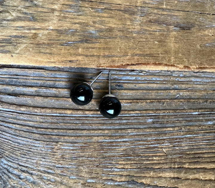 Black jade ball stud earrings with metal posts shown on a rustic wood background