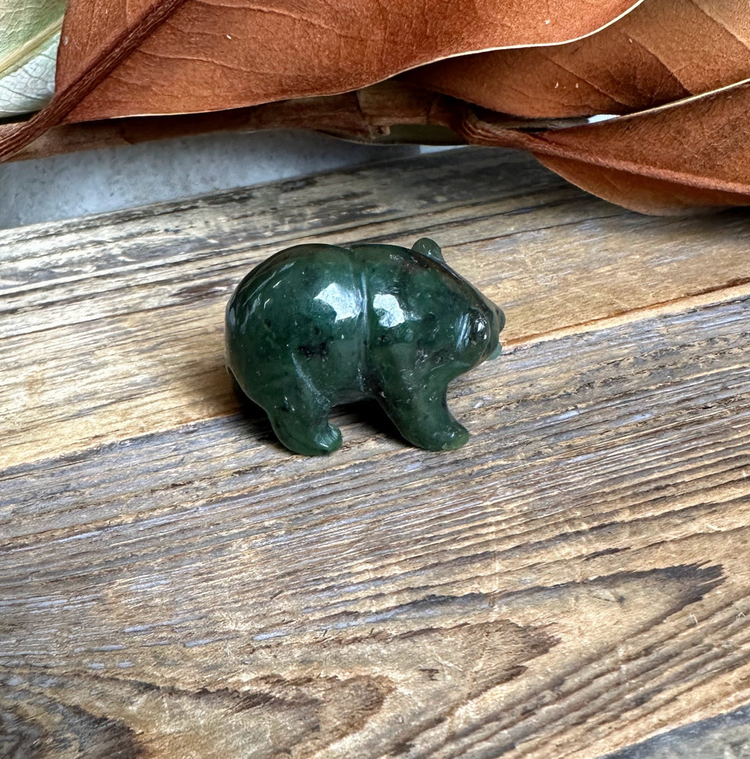 Side view of a dark green jade bear with a lighter jade fish accessory