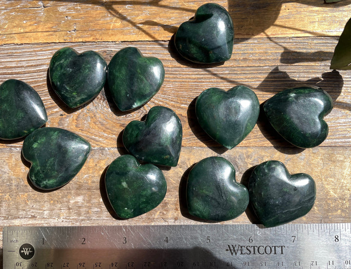 Dark green jade satin heart shapes on a wooden surface with a ruler for scale
