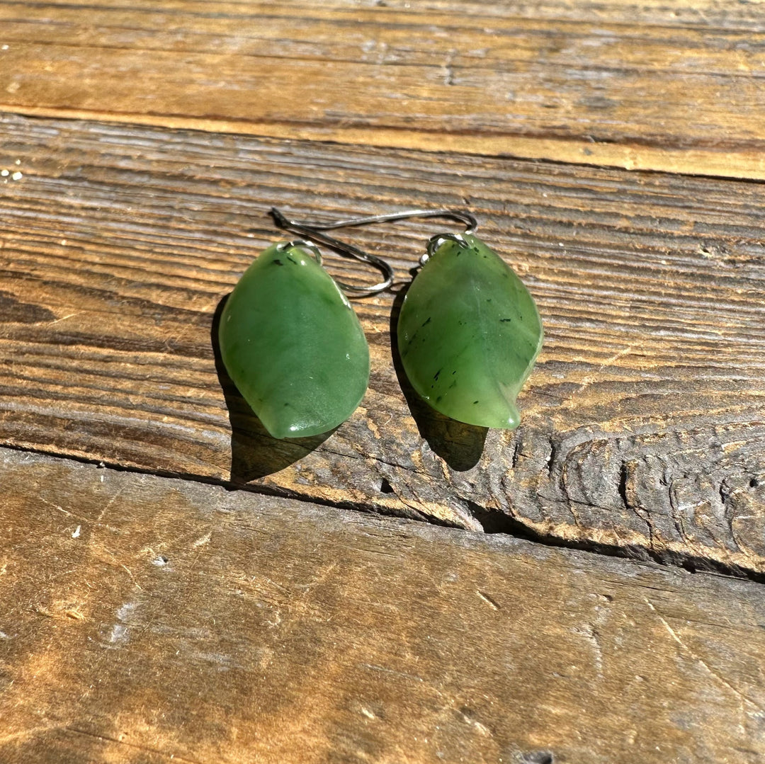 Close up of green jade leaf earrings with silver hooks on aged wood