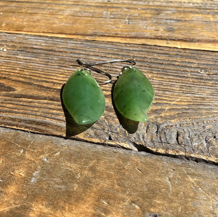 Close up of green jade leaf earrings with silver hooks on aged wood
