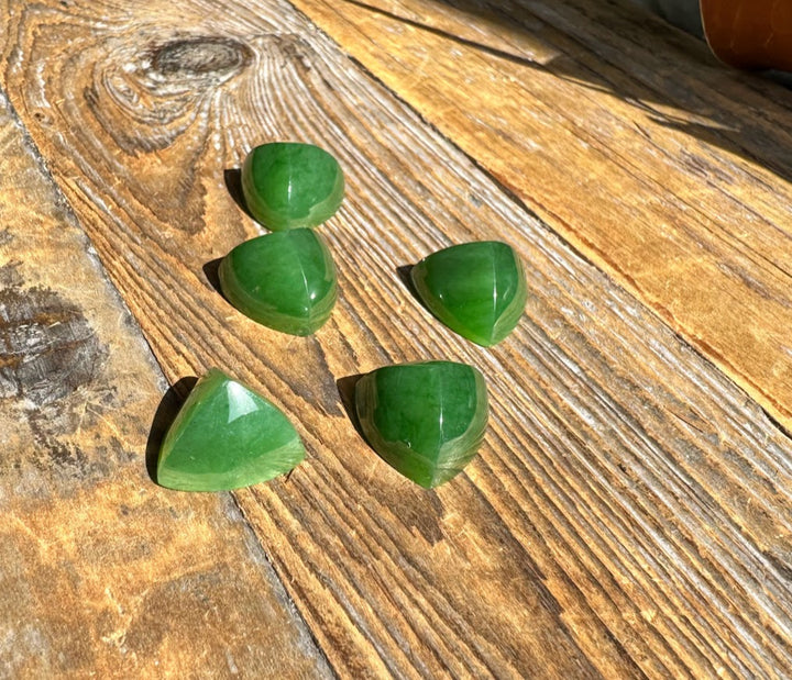 Green jade pyramid cabochons scattered on weathered wood planks