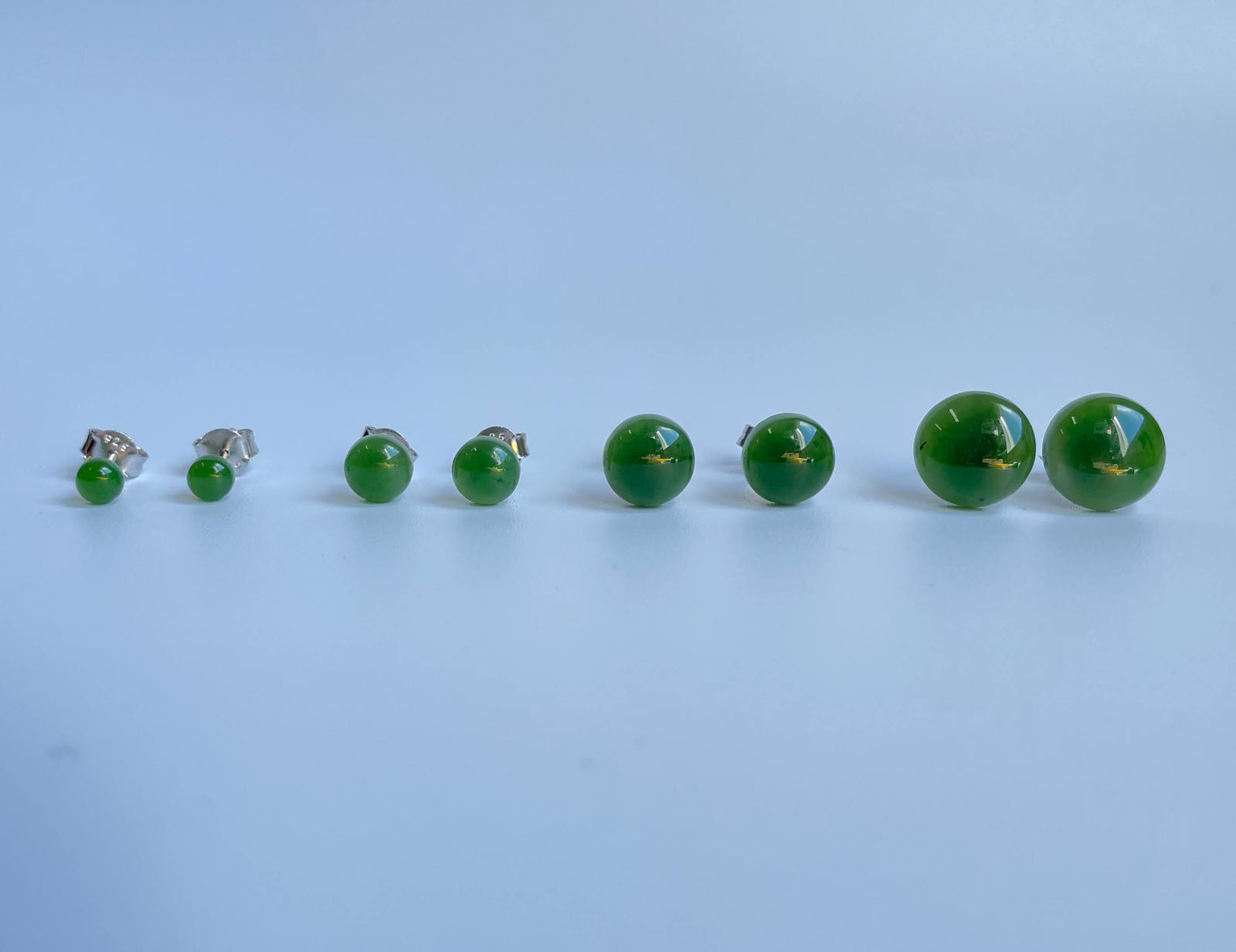 Jade flat stud earrings in multiple sizes arranged in a row from small to large