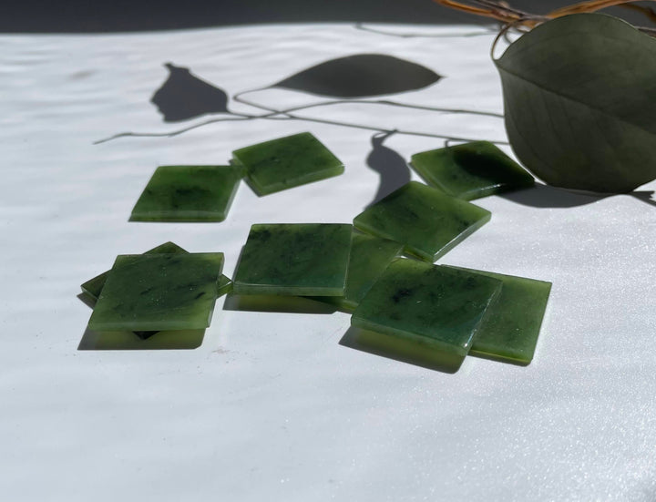 Canadian Jade square cabochons 24.5 x 24.5 mm arranged on a light surface with natural shadows