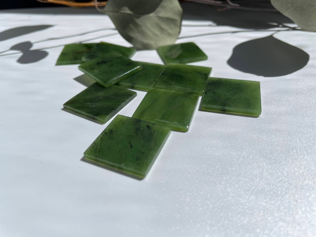 Canadian Jade square cabochons 24.5 x 24.5 mm scattered on a white background