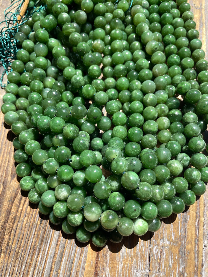 Glossy 8mm green beads piled on a wooden surface.