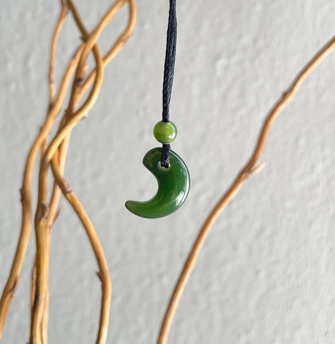 Green jade magatama pendant with a small bead on a black cord.