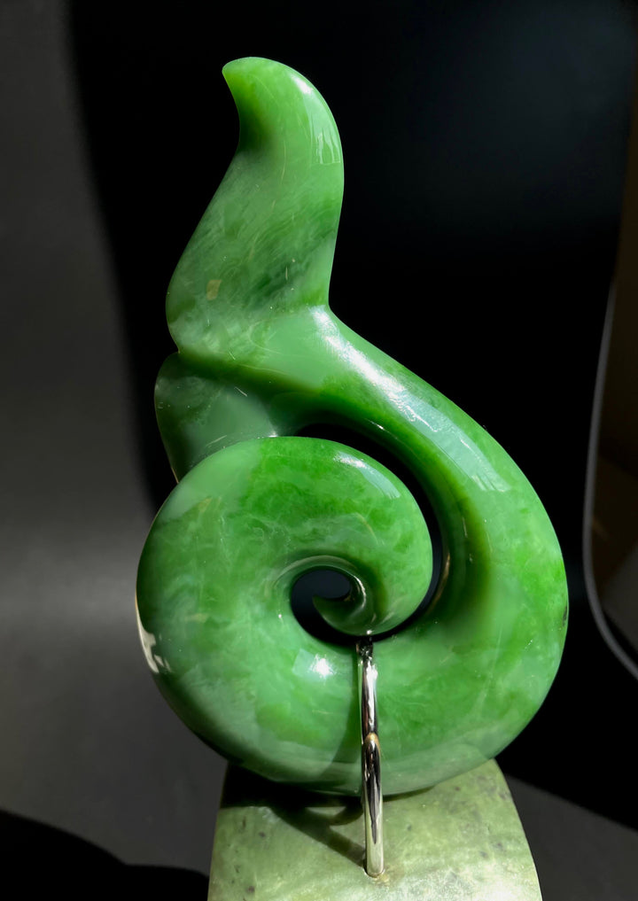 Side view of Jade Whale Tail on Jade Base showing a twisting spiral and glossy green surface.