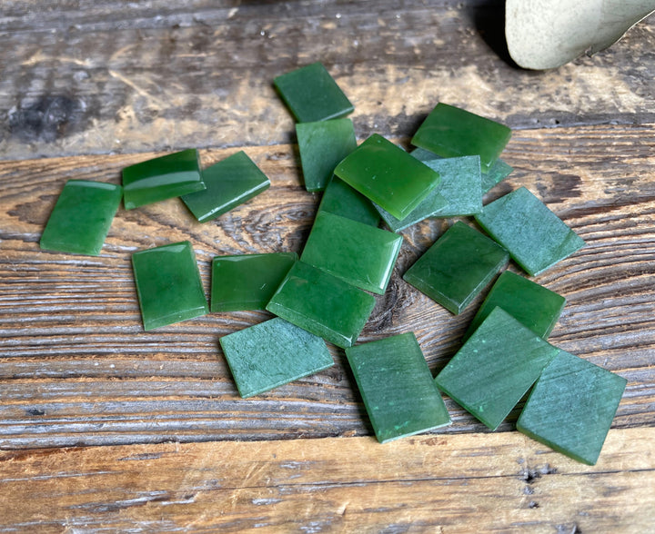 A Grade emerald green rectangle cabochons 17.5x12.5mm arranged on a rustic wooden surface
