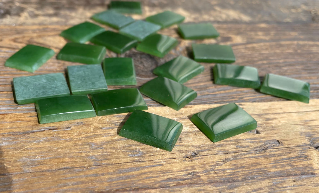 Green rectangular cabochons scattered on a weathered wooden surface