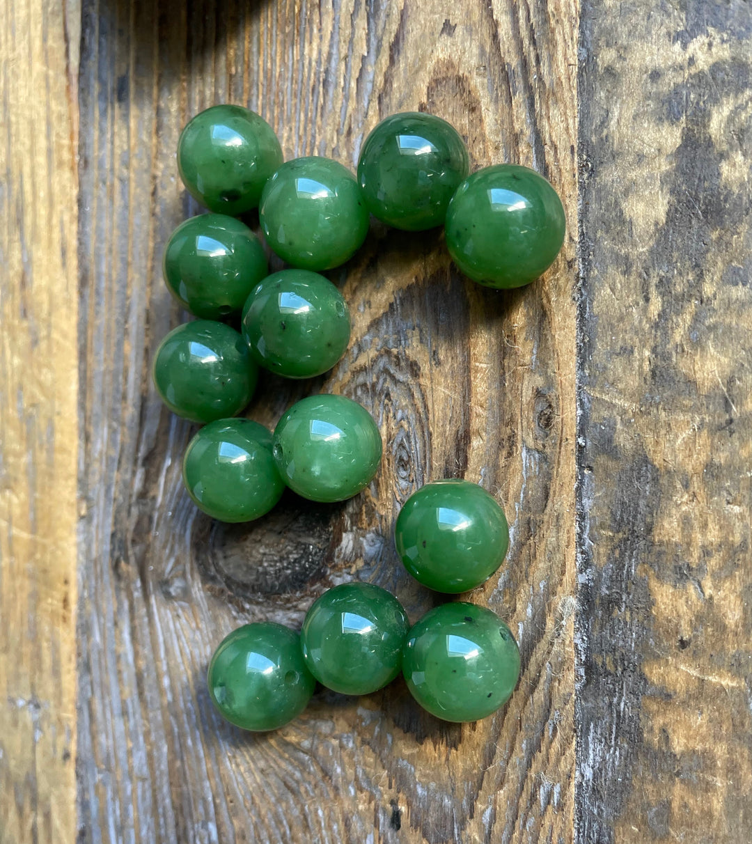 Cluster of polished green jade beads on a weathered wooden surface
