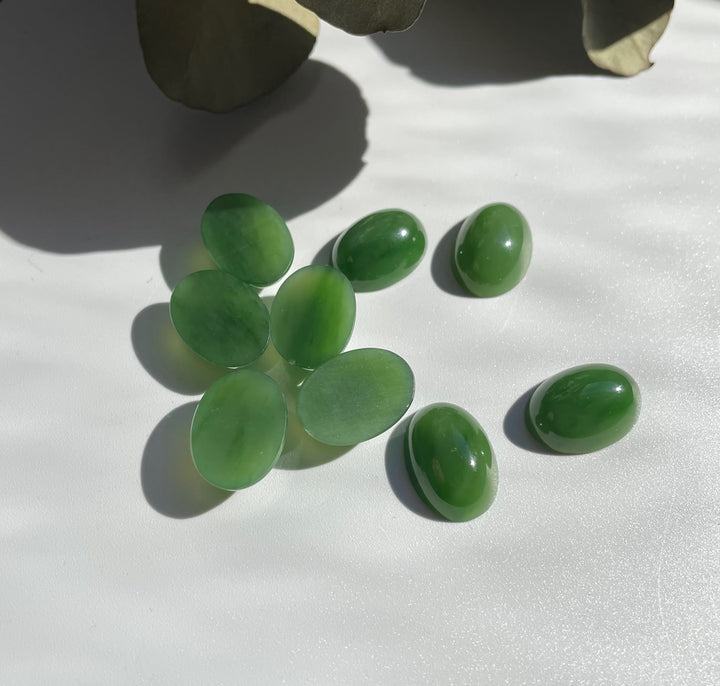 Group of green Siberian jade oval cabochons 18x13 mm on a white surface