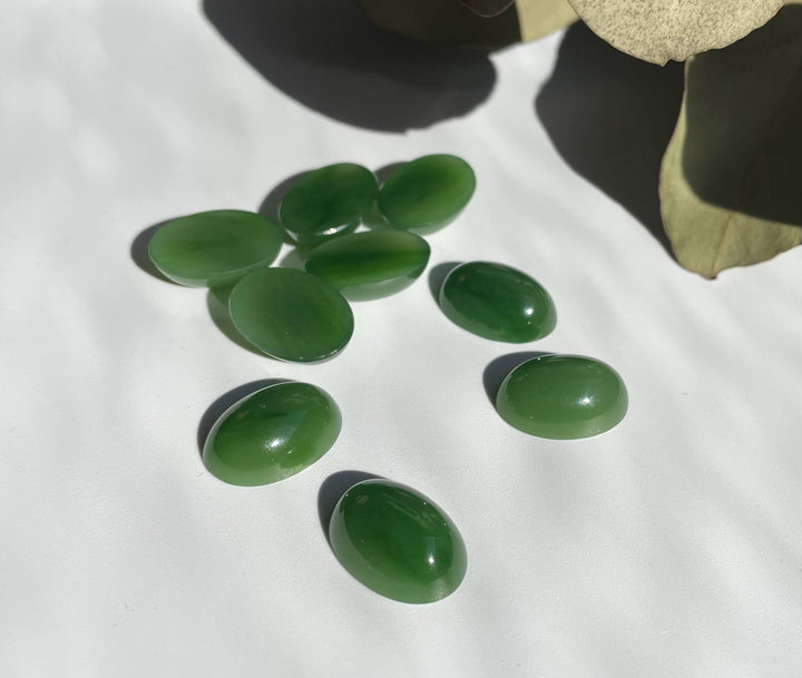 Group of oval AA Grade Siberian Jade cabochons in bright green on white background